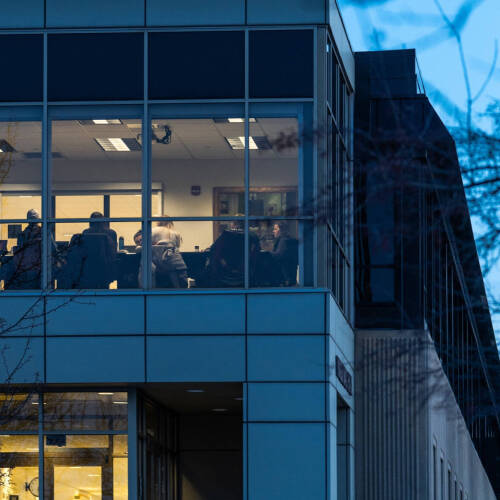 Group sitting in a large space surrounded by glass